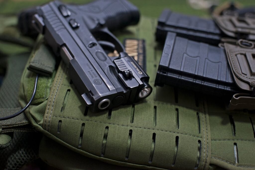 Handgun placed on military gear with tactical accessories, emphasizing modern defense tools.